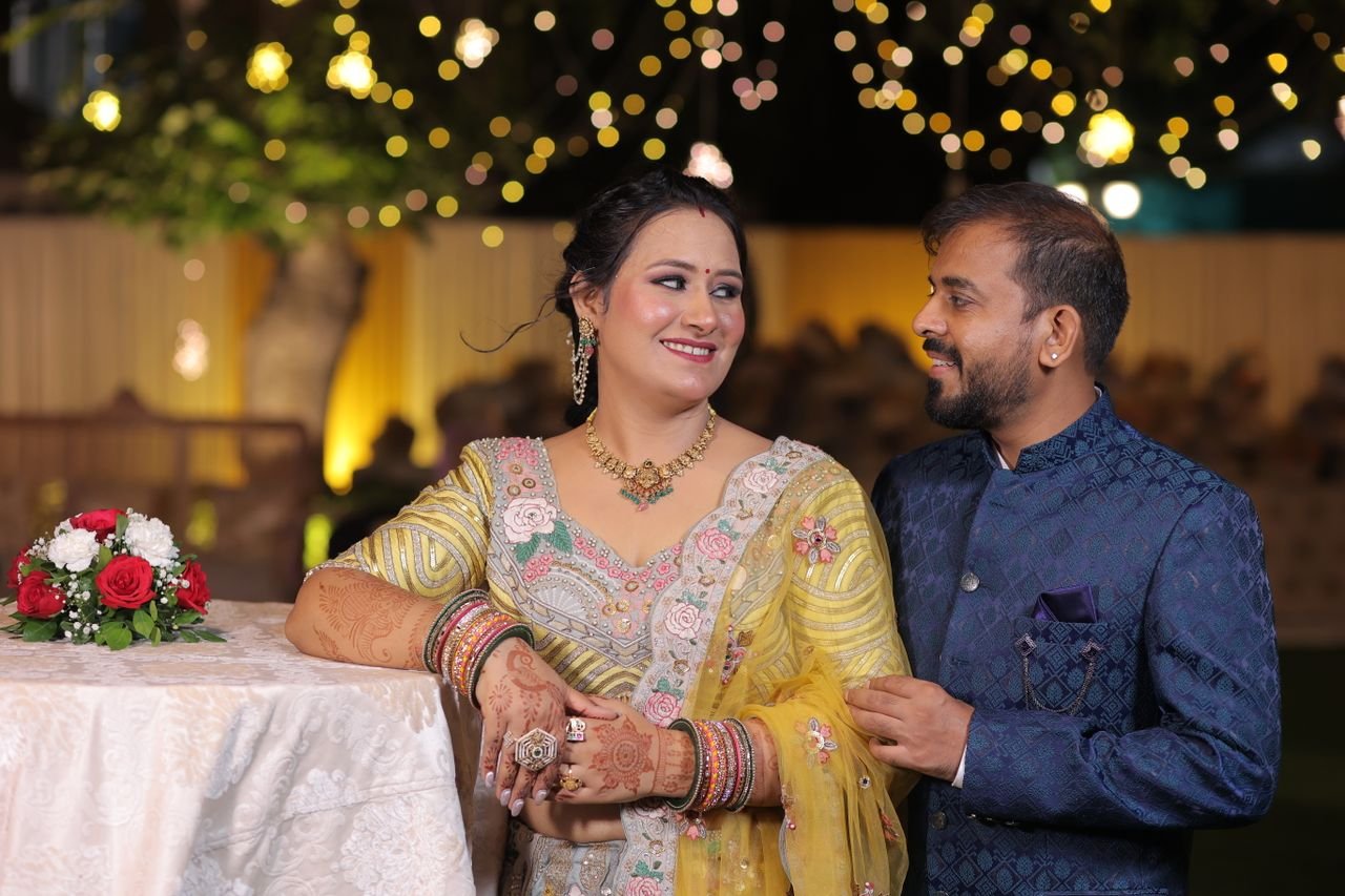 A couple in traditional attire enjoying a joyful moment at an outdoor evening wedding celebration.